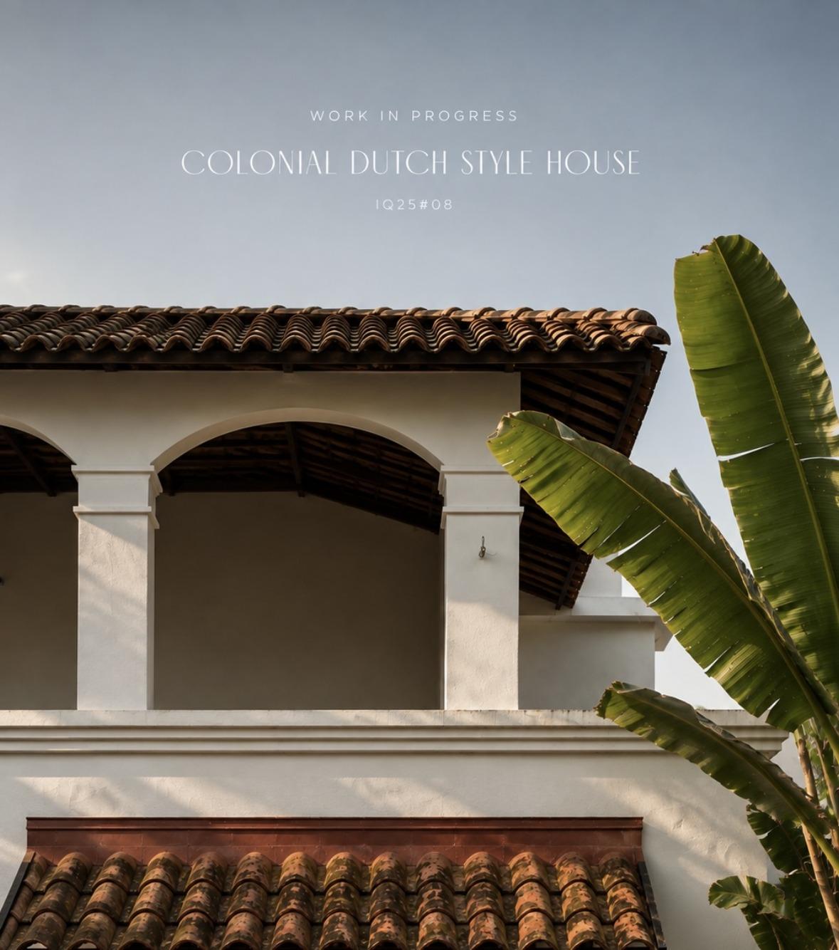 Work in progress: an arched first-floor veranda beneath a clay-tile roof, white lime-plastered columns, a lower tiled awning and banana leaves against a pale morning sky