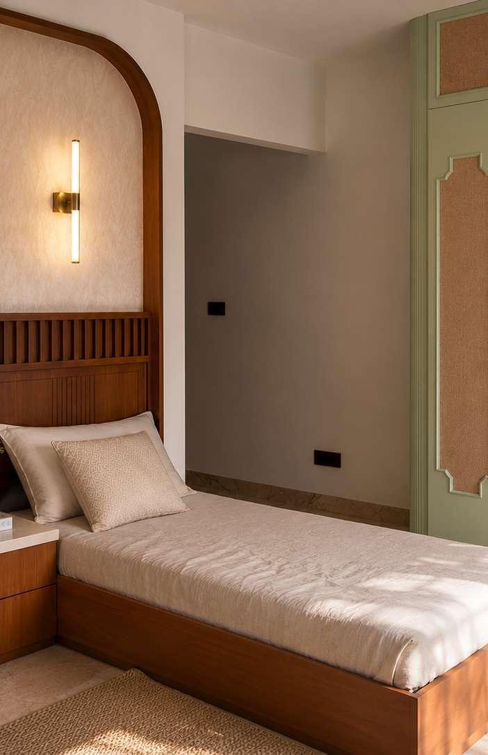 Guest bedroom with a fluted teak bed, an arched headboard wall and a slim brass wall light