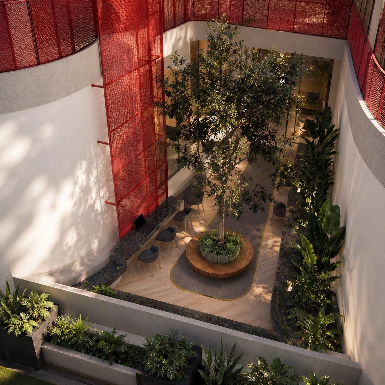 The sunken courtyard: a single tree ringed by a circular timber bench, outdoor workstations and tropical planting beneath the red screen