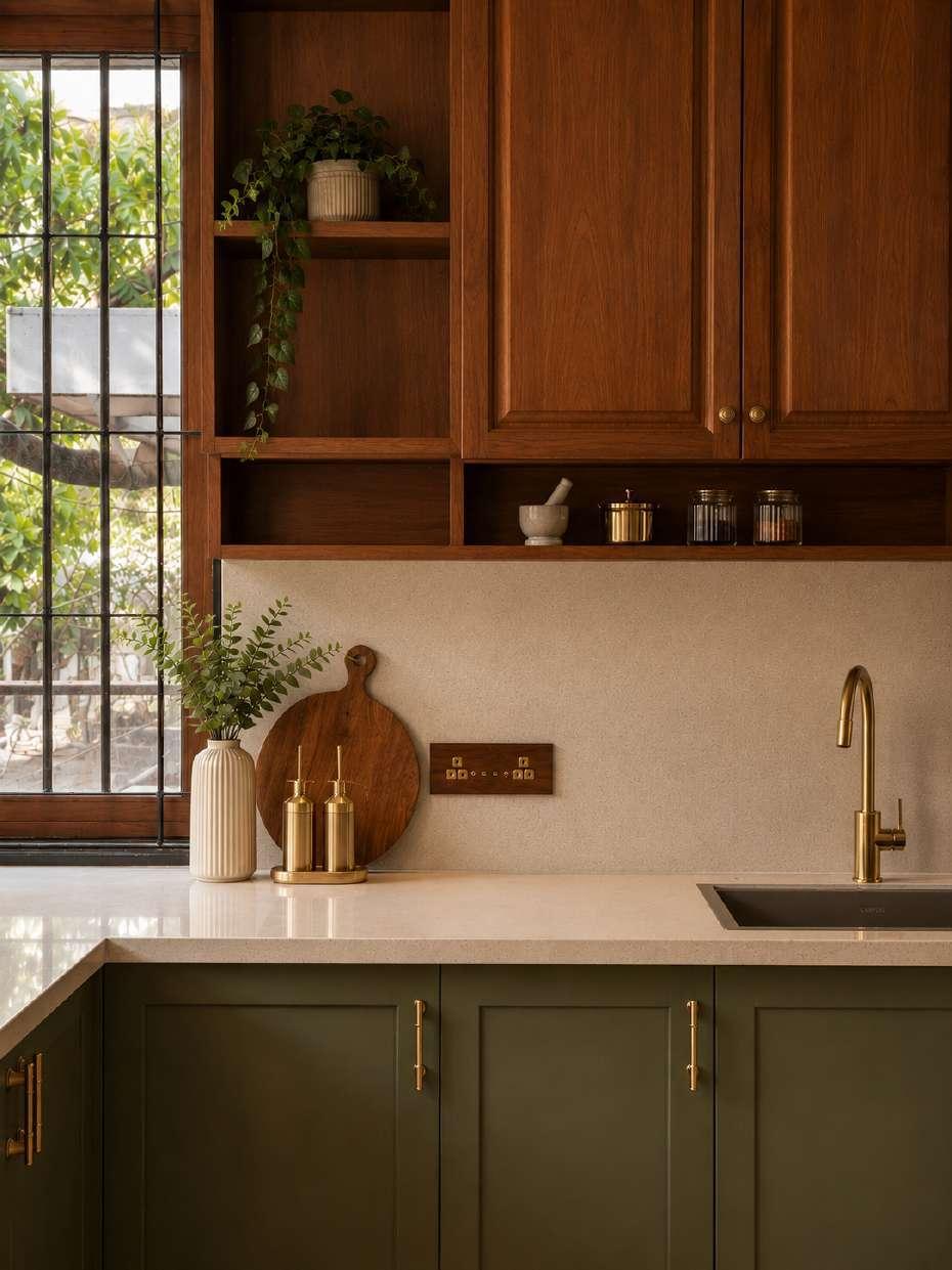 Kitchen with natural teak upper cabinetry, muted olive lower units, a pale stone counter and brushed brass tap and fittings